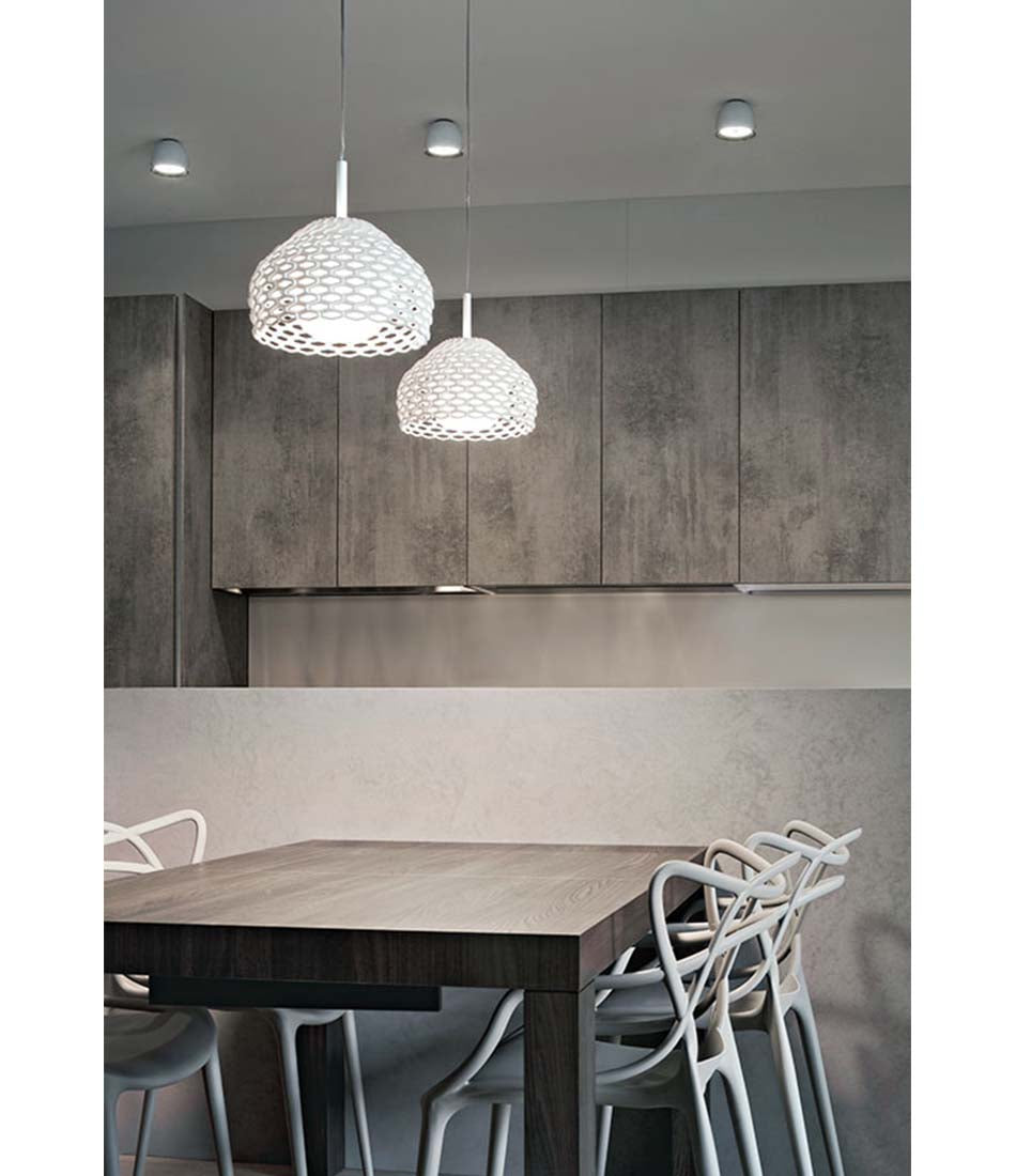 Two Flos Tatou suspension lamps hanging above a dining table and chairs.