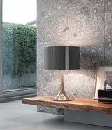 Flos Spun table lamp on a wooden shelf in front of stone wall.