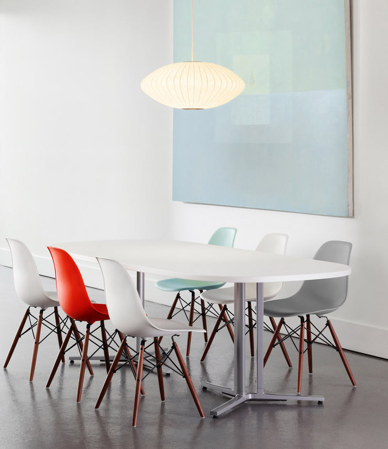 A Herman Miller Nelson Saucer Bubble Lamp hangs over a white dining table and chairs.