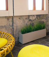 Layer All Day planter in dolphin grey finish next to a chair under a window.