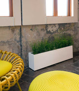 Layer All Day planter in white gloss finish next to a chair under a window.