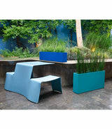 A royal blue Layer All Day planter and teal Everyday planter next to picnic table in a courtyard.